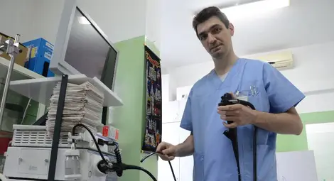 Д-р Кулински показва апарат гастроскоп, с който се проверява заболяванията на дебелото черво.