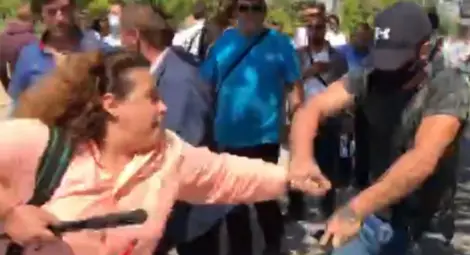 Младият мъж с маска, шапка и тъмна фланелка първо беше сред хората, провокирали сблъсъци с антиправителствени протестиращи, а след това няколко пъти отне със сила телефона на журналиста от &bdquo;Свободна Европа&ldquo; Полина Паунова и го изхвърли.