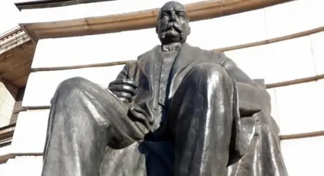 Бронзовата фигура на Евлоги Георгиев на парадния вход на СУ &bdquo;Св. Климент Охридски&ldquo;.