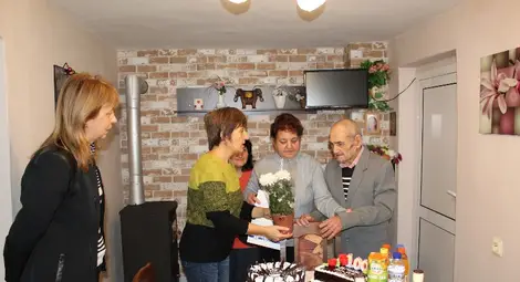 Дядо Георги получи поздравителен адрес от кмета Пламен Стоилов, който му беше връчен от шефката на социалните дейности в общината Катя Петрова /крайната вляво/.Снимка: Община Русе