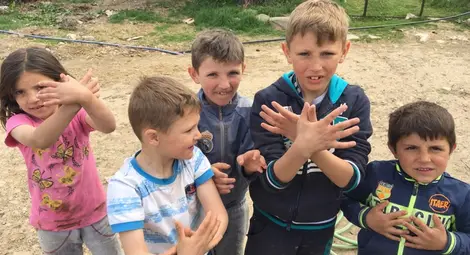 Малки албанчета пресъздават двуглавия орел от албанския герб с ръцете си. / БГНЕС