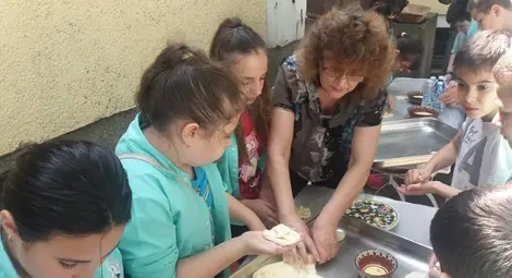 Учителката по труд и творчество Милена Тодорова помага на ученици да омесят питки.  Снимка:Утро
