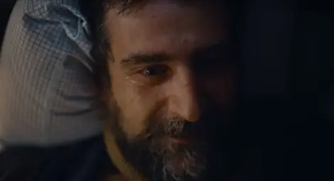 Кадър от рекламата, за чието спиране се настоява - Христо лежи разплакан в койката си и мечтае за семейството си.