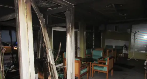 Пластмасовата дограма на входа е деформирана от огъня, изгорели са и завеси. 			Снимки: Русе Медиа