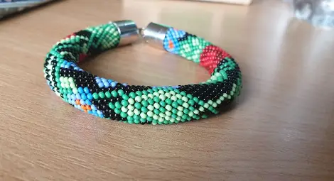 Съдебен помощник тъче бижута от мъниста на ръчно направен стан